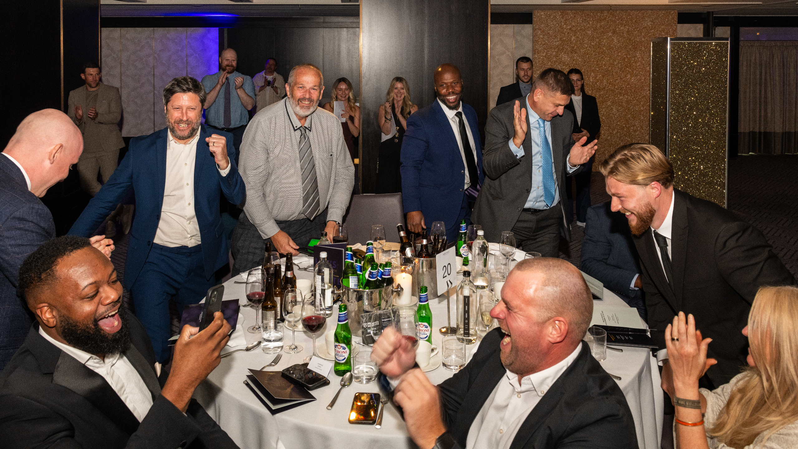 Excellence Awards 2025 9 A lively banquet scene with people celebrating around a table filled with drinks and plates.