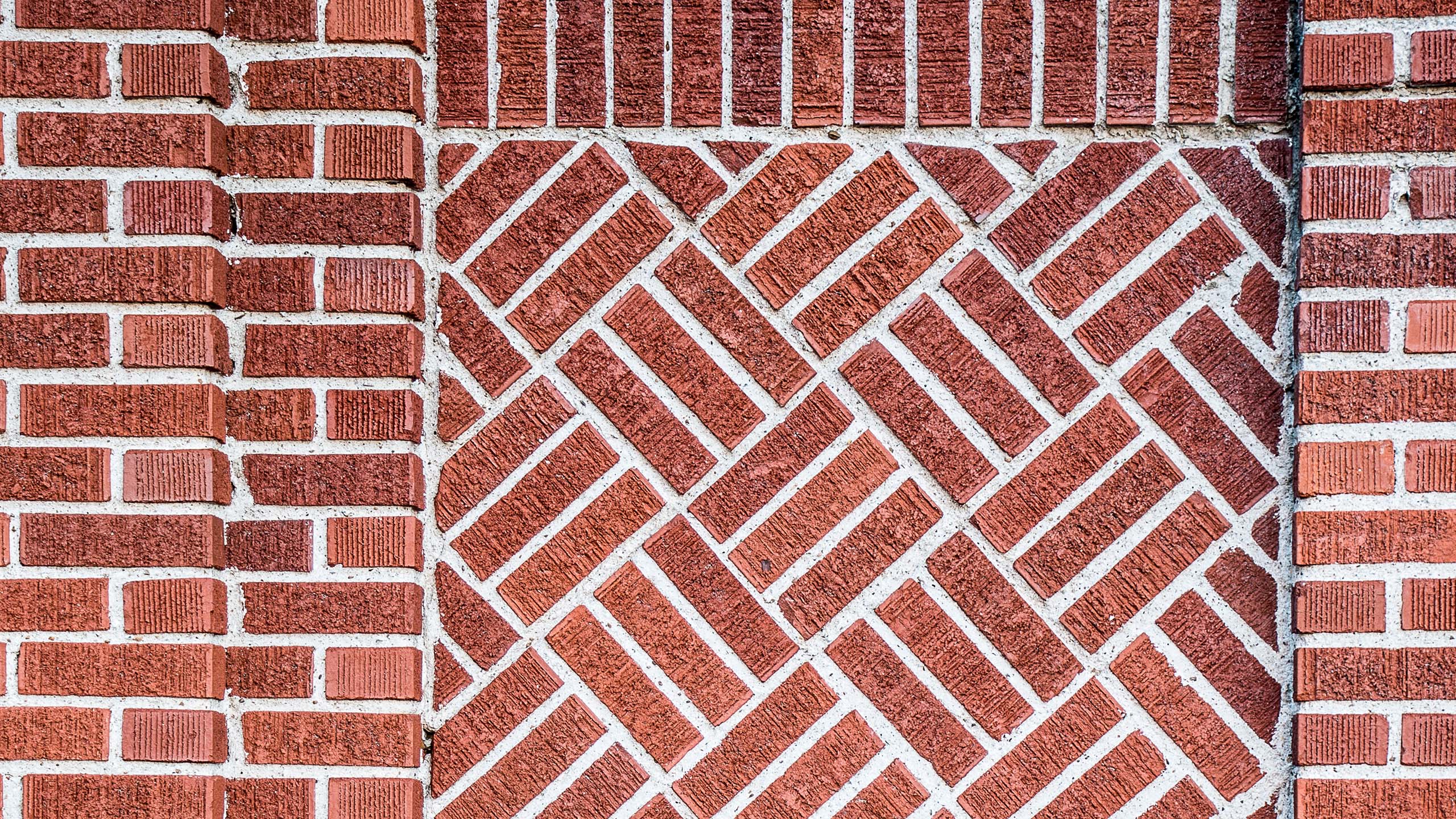 Intricate Brick Wall Pattern | Architectural Masonry Design Brick wall featuring a central herringbone pattern framed by traditional horizontal brickwork, showcasing detailed masonry craftsmanship and architectural design.