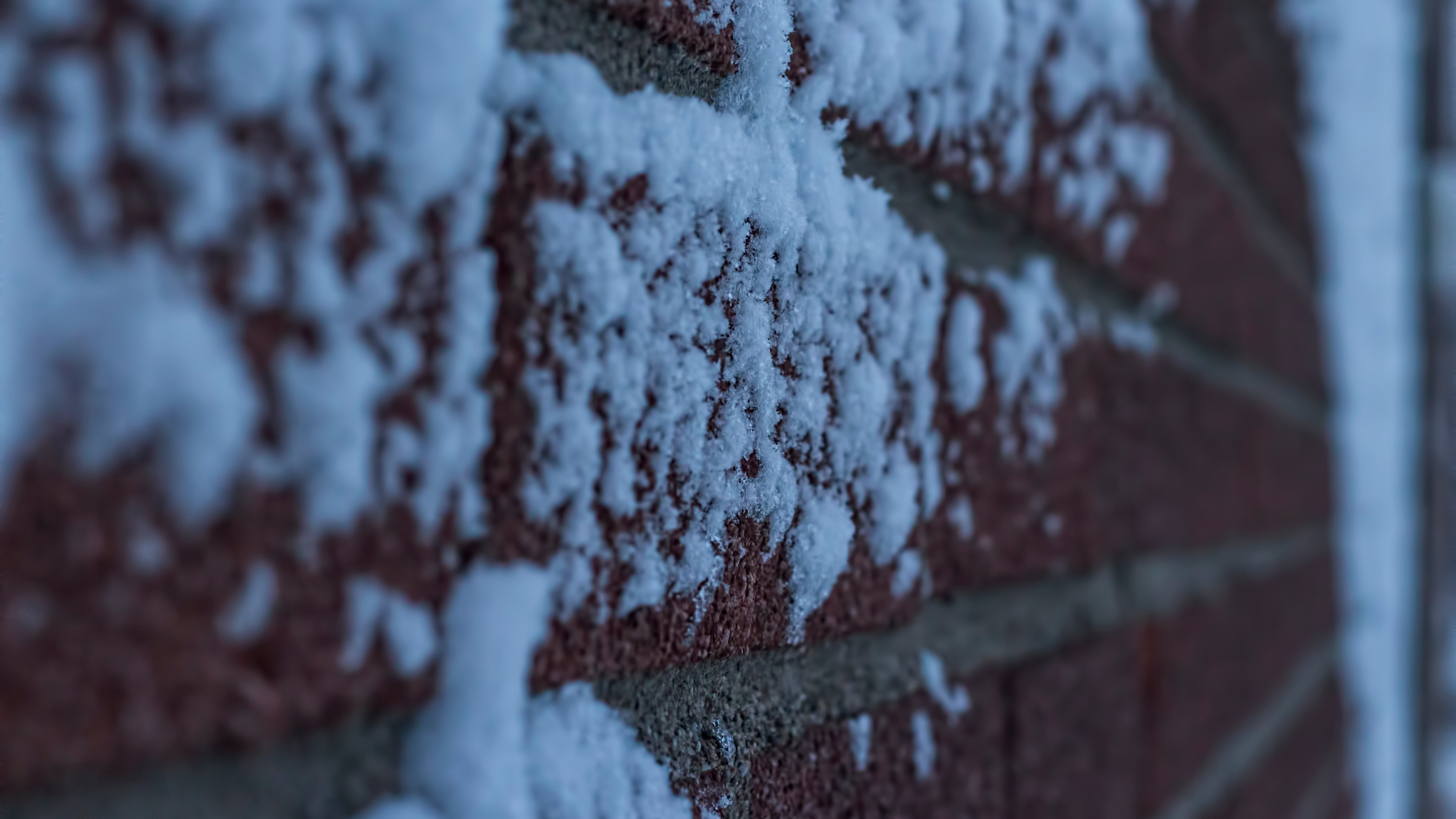 Snow-Covered Brick Wall Texture | Winter Masonry Detail A close-up image of a brick wall with patches of snow on it.