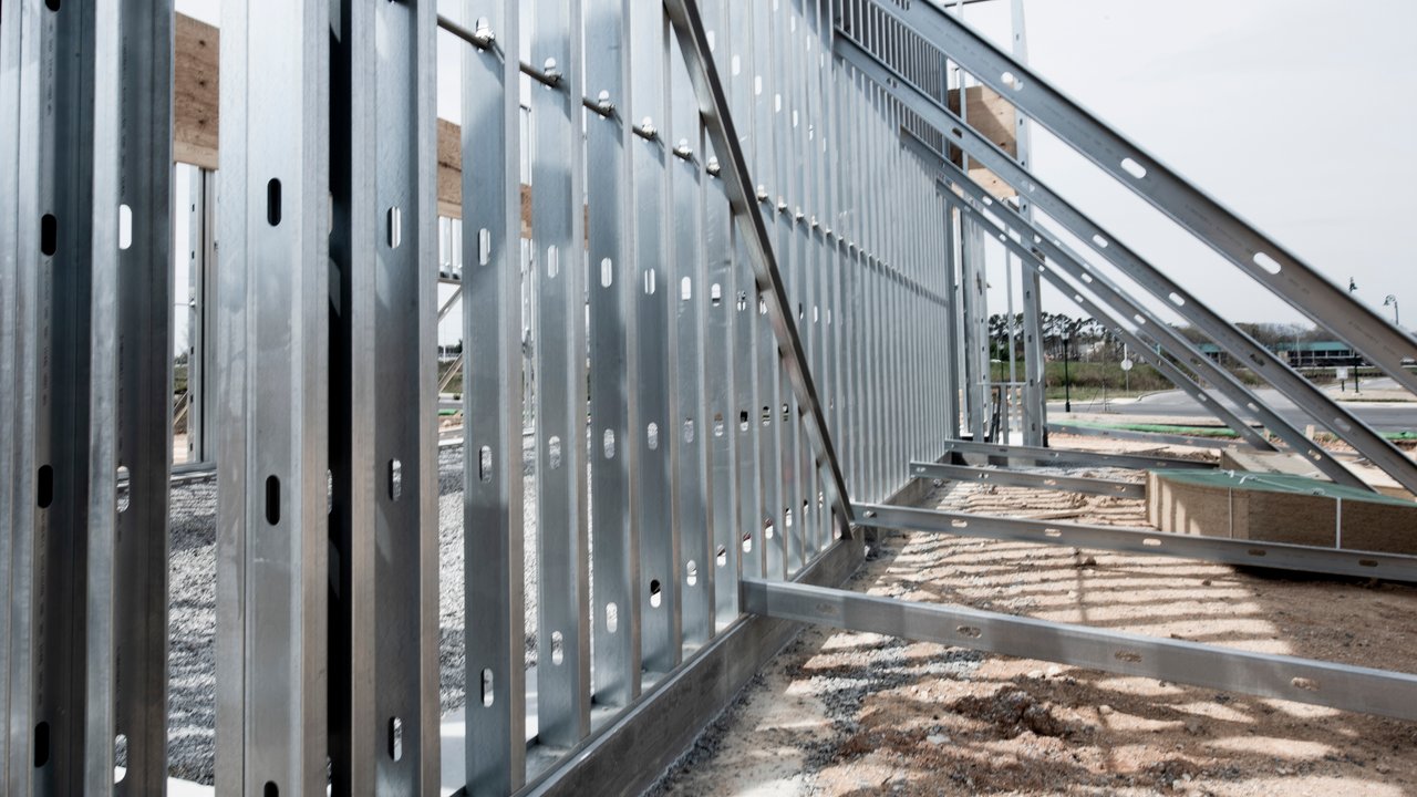 Close-up view of a steel frame structure under construction, showing metal studs, beams, and diagonal braces at a modern building site.